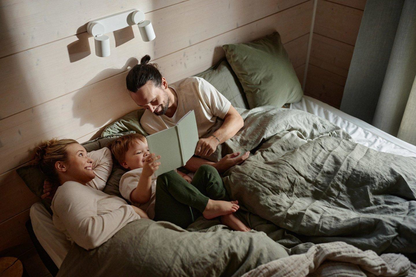 perhe makaa sängyllä aamulla hirsitalossa